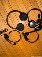 Four headsets arranged on wood floor displaying earcups, headbands, cords visible