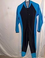 Full view of black and blue men’s diveskin wetsuit hanging to show overall design and condition