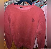 Front view of red The North Face crewneck sweatshirt on hanger