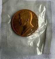 Obverse of sealed bronze JFK inauguration coin in plastic