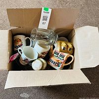 Top view of open box showing assorted ceramic and glass mugs inside
