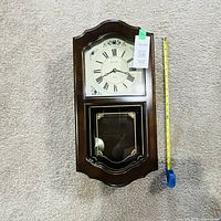 Full view of Bulova wooden wall clock with measuring tape indicating height