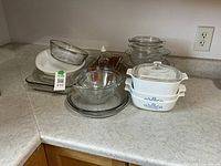 Group of casserole dishes, mixing bowls, pie pans and loaf pan on countertop