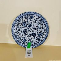 Front view of blue and white floral ceramic plate with MaxSold tag