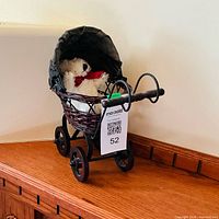 Front view of wicker pram with teddy bear inside