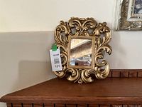Front view of ornate gold framed mirror on shelf