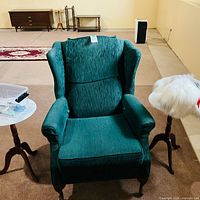 Front view of green wingback armchair showing upholstery, shape and legs