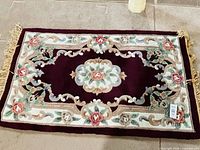 Full view of burgundy floral hand-hooked rug with fringe