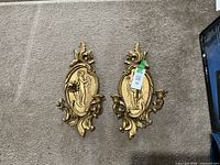 Pair of gold-tone wall candle sconces on carpet