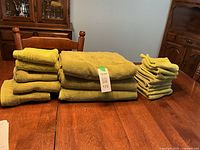 Stacked olive green towels showing bath sheets, hand towels, facecloths
