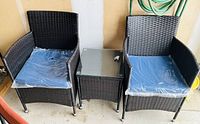 Two wicker armchairs with blue cushions and matching side table