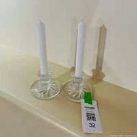 pair of glass candle holders with white taper candles inserted