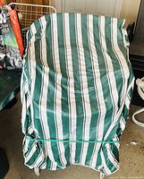 Stack of outdoor chairs covered by green-and-white striped fabric cover