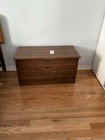 Front view of rectangular wooden chest with lid closed showing carved fan motif and lock