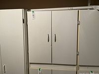 Front view of closed white laminate cupboard alongside others