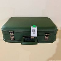 Closed avocado green hardshell suitcase showing handle, latches, exterior condition