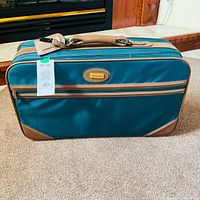 Front view of dark green Jaguar suitcase showing logo, leather trim and front zip pocket