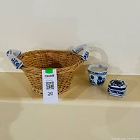 Overall view of wicker basket with ceramic handles and two accompanying blue-white trinket boxes