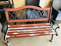Full view of wood and metal outdoor bench showing seat slats, decorative metal back, arms, and legs
