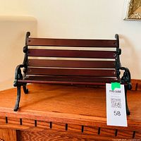 Front view of miniature bench showing wood slats and cast metal sides, size tag visible