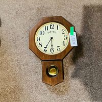 Front view of wooden Bulova wall clock showing dial and pendulum