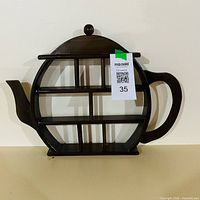 Front view of wooden teapot shaped trinket shelf showing compartments