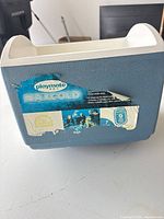 Front view of blue Igloo Playmate MaxCold cooler with torn label