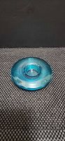 Oblique view of blue glass ribbed candle holder showing disc shape and central recess