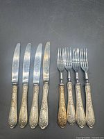 Group shot of six knives and four forks laid out side by side