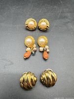 All three earring pairs laid out on dark surface