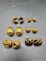 Overview of all six earring pairs laid out on dark surface