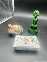 Group shot showing all three items: porcelain trinket box, green hobnail glass bottle, multicoloured bird figurine