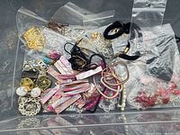 Overview of assorted jewellery items in plastic bin