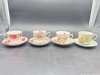 Four mismatched teacup and saucer sets lined up