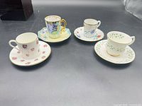 Group shot of four demitasse cup and saucer pairs showing overall condition and designs