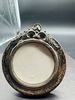 Front view showing circular sterling frame with ornate crest
