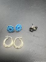 All three pairs of earrings side by side on dark surface