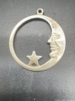 Front view of round sterling pendant showing crescent moon and star design