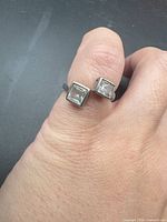 Top view of sterling bypass ring on finger showing twin square stones