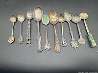 All eleven sterling silver souvenir spoons lined horizontally
