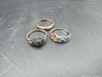 Three sterling silver rings laid out on black background
