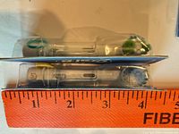 Side view of two blister-sealed Oral-B brush heads against ruler showing approximate 3 inch length
