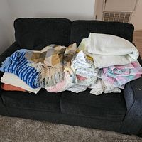 Pile of assorted blankets and linens on sofa