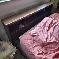 Wooden bookcase headboard attached to bed frame and mattress
