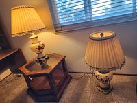 Two matching ceramic table lamps with pleated shades on floor and side table