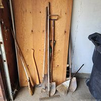 Full group of long-handled tools against wall