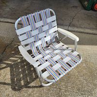 Front angled view of folded-out beach chair showing frame, webbing, and armrests