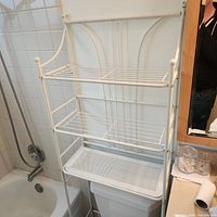 Full view of white metal rack over toilet showing three shelves