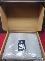 Open shipping box showing sealed light grey sheet set and lot tag