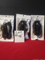 Three sealed black coiled adapter cords in retail pouches with barcode labels displayed upright